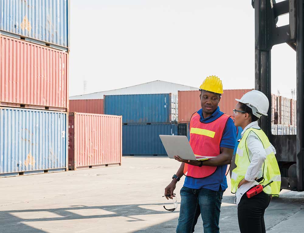 Global Logistics workers in safety vests working on a laptop