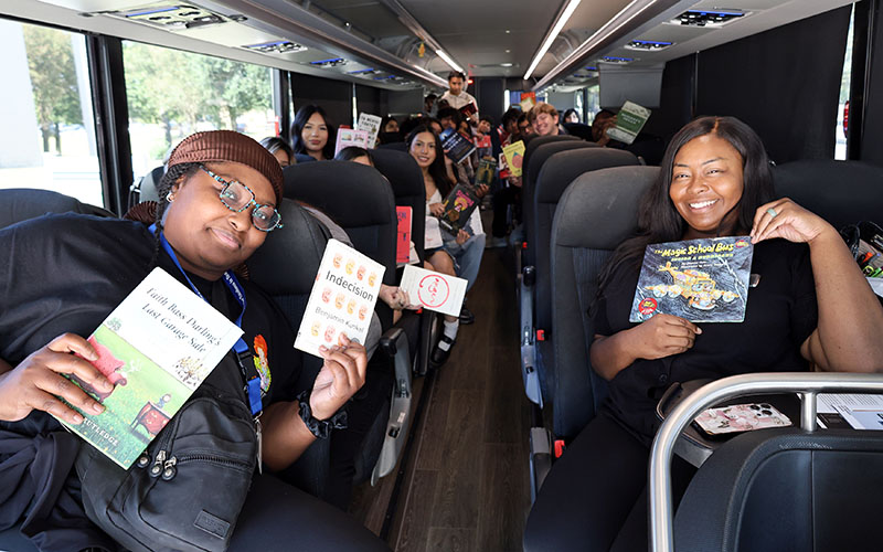 Professors and students holding books while sitting on charter bus